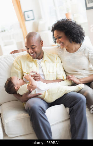 Padre sorridente alimentazione bambino sul divano Foto Stock