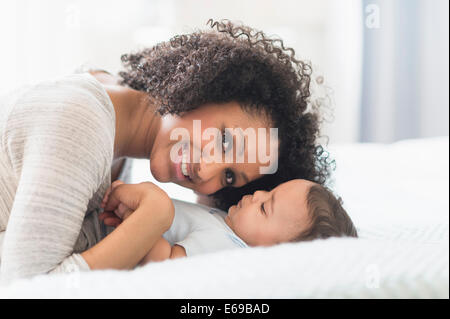Razza mista madre giocando con il bambino sul letto Foto Stock