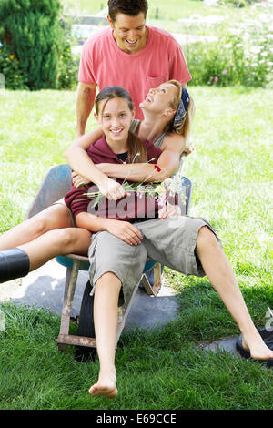 L'uomo spingendo la moglie e la figlia in carriola Foto Stock