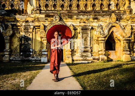 Uomo asiatico che porta ombrellone da decorativi tempio Foto Stock