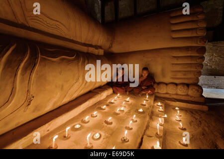 Monaci asiatici accendendo candele nel tempio Foto Stock