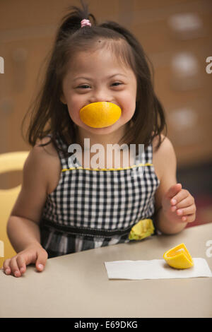 Razza mista ragazza con la sindrome di Down mangiare la frutta Foto Stock