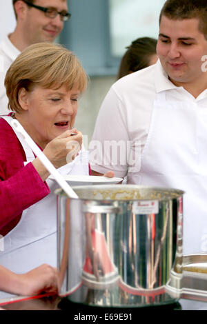 Bonn, Germania. 19 Ago, 2014. Il cancelliere tedesco Angela Merkel tenta uno stufato in una cucina di campo dell'Ordine di San Giovanni di Bonn, Germania, 19 agosto 2014. Il cancelliere tedesco ha visitato l'Ufficio federale della protezione civile e di assistenza di emergenza per conoscere il lavoro di ufficio e dell'Agenzia federale per il rilievo tecnico (THW). Foto: OLIVER BERG/DPA/Alamy Live News Foto Stock