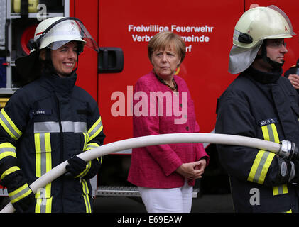 Bonn, Germania. 19 Ago, 2014. Il cancelliere tedesco Angela Merkel (C) si erge tra volontario vigili del fuoco a Bonn, Germania, 19 agosto 2014. Il cancelliere tedesco ha visitato l'Ufficio federale della protezione civile e di assistenza di emergenza per conoscere il lavoro di ufficio e dell'Agenzia federale per il rilievo tecnico (THW). Foto: OLIVER BERG/DPA/Alamy Live News Foto Stock