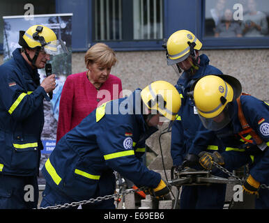 Bonn, Germania. 19 Ago, 2014. Il cancelliere tedesco Angela Merkel (2-L) si erge tra i membri dell'Agenzia federale per il rilievo tecnico (THW) di Bonn, Germania, 19 agosto 2014. Il cancelliere tedesco ha visitato l'Ufficio federale della protezione civile e di assistenza di emergenza per conoscere il lavoro di ufficio e dell'Agenzia federale per il rilievo tecnico (THW). Foto: OLIVER BERG/DPA/Alamy Live News Foto Stock