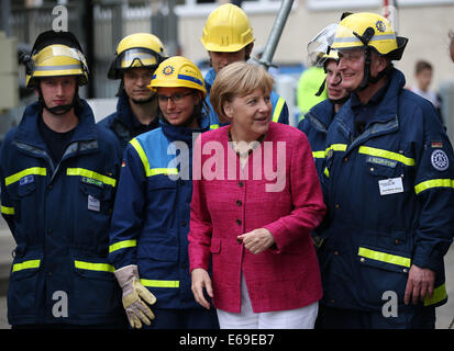 Bonn, Germania. 19 Ago, 2014. Il cancelliere tedesco Angela Merkel (C) si erge tra i membri dell'Agenzia federale per il rilievo tecnico (THW) di Bonn, Germania, 19 agosto 2014. Il cancelliere tedesco ha visitato l'Ufficio federale della protezione civile e di assistenza di emergenza per conoscere il lavoro di ufficio e dell'Agenzia federale per il rilievo tecnico (THW). Foto: OLIVER BERG/DPA/Alamy Live News Foto Stock