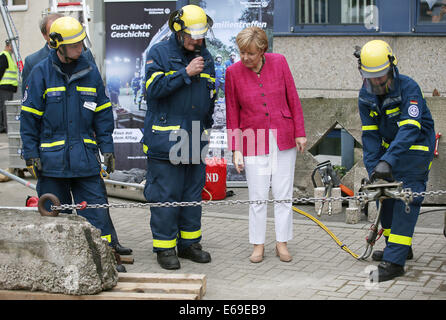 Bonn, Germania. 19 Ago, 2014. Il cancelliere tedesco Angela Merkel (2-R) si erge tra i membri dell'Agenzia federale per il rilievo tecnico (THW) di Bonn, Germania, 19 agosto 2014. Il cancelliere tedesco ha visitato l'Ufficio federale della protezione civile e di assistenza di emergenza per conoscere il lavoro di ufficio e dell'Agenzia federale per il rilievo tecnico (THW). Foto: OLIVER BERG/DPA/Alamy Live News Foto Stock