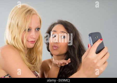 Fidanzate tenendo selfie con un telefono cellulare mentre baciare Foto Stock