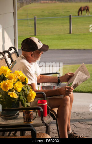 Uomo maturo sul ponte posteriore del suo ranch Home leggendo il giornale del mattino , STATI UNITI Foto Stock