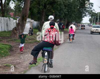 Noleggio taxi dando portanza a ben vestito nero giovane donna africana di equitazione sella laterale sulla periferia della città di Nakuru Kenya Foto Stock