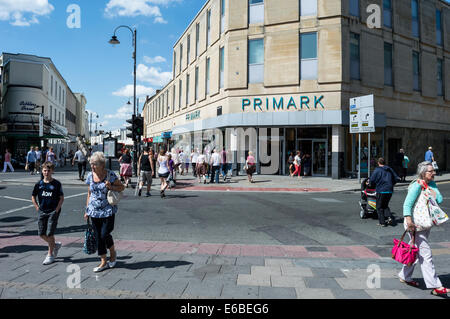 Gli amanti dello shopping attraversando la strada al di fuori di Primark in Cheltenham town center Foto Stock