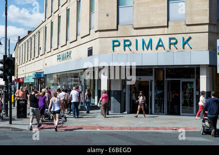 Gli amanti dello shopping attraversando la strada al di fuori di Primark in Cheltenham town center Foto Stock