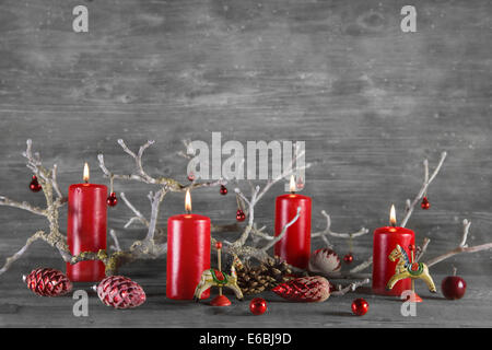 Quattro rosso cera di masterizzazione avvento candele di legno su sfondo grigio. Foto Stock