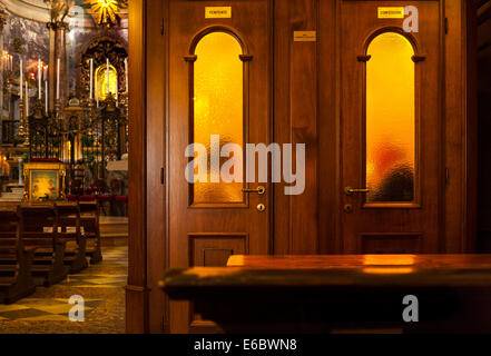 Sacerdote audizione confessione nel confessionale booth nella Chiesa cattolica romana con il Santuario della Madonna di San Luca a Bologna Foto Stock