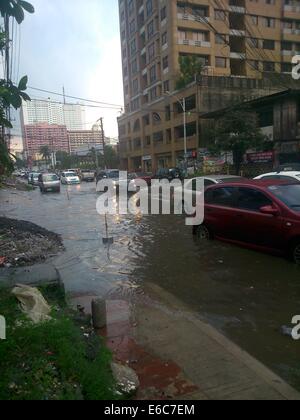 Quezon City, Filippine. 20 Agosto, 2014. I veicoli sono visibili passando attraverso l'allagato Panay Avenue in Quezon City. Forti piogge monsoniche intorno a 2:30 pm che durò meno di un ora causato inondazioni. Il drenaggio / di fognature di Panay Avenue sono state molte volte riabilitato nel 2013 in modo che possa sopportare il notevole volume di acqua delle piogge ma purtroppo non riuscita. Tonnellate di rifiuti che sporchi il drenaggio è stata osservata dopo il diluvio cessa. Credito: Sherbien Dacalanio / Alamy Live News Foto Stock