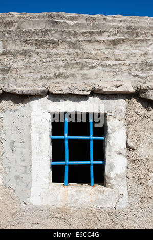 Una finestra blu con barre di acciaio sul Mediterraneo casa di pietra Foto Stock