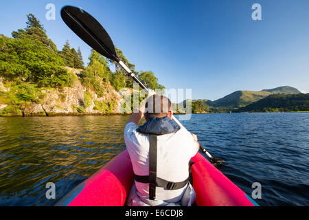 Un uomo di mezza età paddling in un kayak inflateable sull'Ullswater nel distretto del lago, UK. Foto Stock