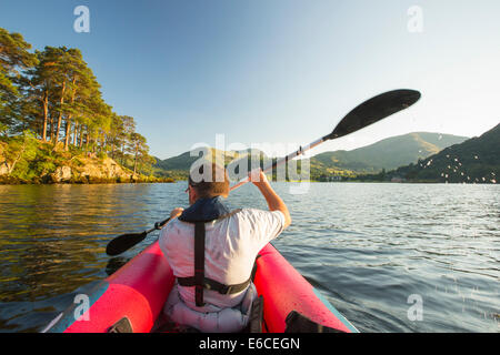 Un uomo di mezza età paddling in un kayak inflateable sull'Ullswater nel distretto del lago, UK. Foto Stock