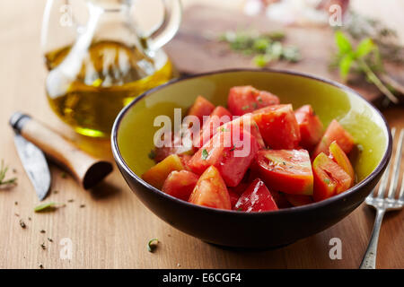 Ciotola di materie insalata di pomodoro con olio d'oliva ed erbe aromatiche Foto Stock