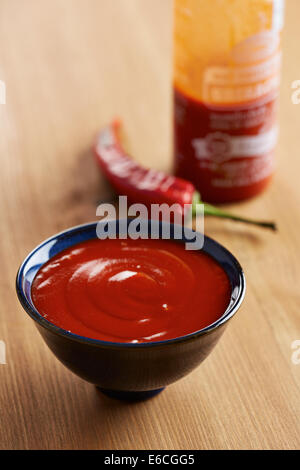 Ciotola e bottiglia di salsa sriracha Foto Stock