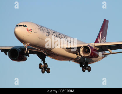 Virgin Atlantic Airways Airbus A330-300 long haul jet del passeggero aereo sulla rotta di avvicinamento al tramonto contro un cielo blu chiaro. Primo piano vista frontale. Foto Stock