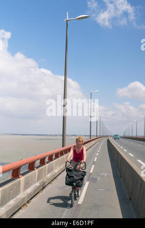 Donna matura ciclismo oltre l'île de Ré ponte tra La Pallice vicino a La Rochelle e Sablanceaux., Francia, Europa Foto Stock