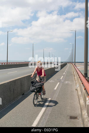 Donna matura ciclismo oltre l'île de Ré ponte tra La Pallice vicino a La Rochelle e Sablanceaux., Francia, Europa Foto Stock