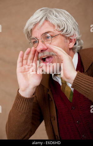 Capelli grigi uomo vecchio, utilizzando entrambe le mani per amplificare la sua voce mentre urlando. Foto Stock