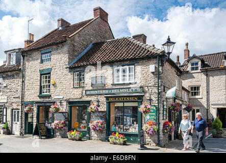 Gli acquirenti e i turisti al di fuori di cacciatori delicatessen in Helmsley market place Foto Stock