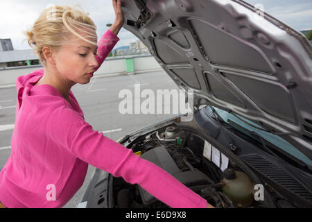 Donna ispezione broken auto motore. Foto Stock