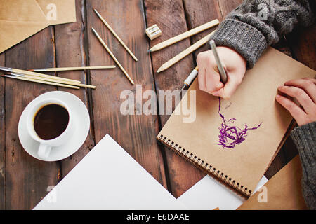 Immagine della tazza di caffè e oggetti per il disegno a mano e artista mani disegno uomo nel blocco note Foto Stock