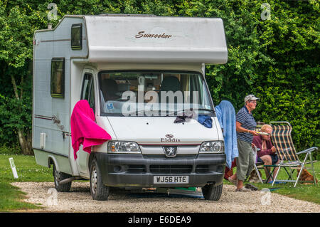 Una coppia di anziani al di fuori della loro motorhome su un caravan club campeggio pitch in Inghilterra, Regno Unito. Foto Stock