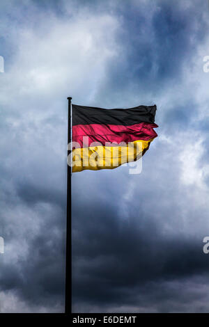 Nuvole temporalesche raccolta dietro la bandiera tedesca, simbolico della crisi politica, la guerra o disordini. Foto Stock