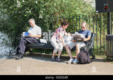 Pomeriggio estivo all'Hyde Park di Londra UK. Immagini di persone su una panchina nel parco di lettura e godendo di una calda giornata estiva Foto Stock