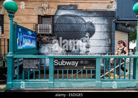 Una donna entra nella metropolitana passato un Bushwick murale collettivo nel quartiere Bushwick di Brooklyn a New York Foto Stock