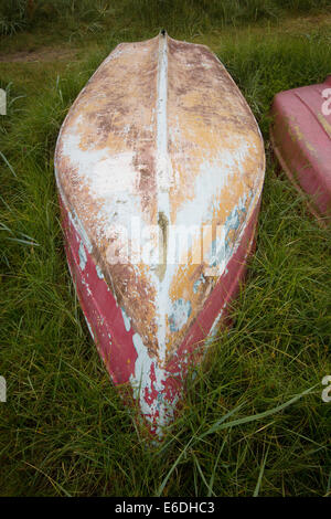 Weathered capovolto le barche a remi in rosso e colori ocra sull'erba Foto Stock
