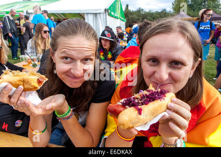 Due ragazze mangiano gli Hotdog da fast food, salsiccia in un boccone con senape, gente che mangia cibo Prague Letna Park, Repubblica Ceca mangiare malsano Foto Stock