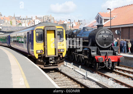 Partenza del 1025 Middlesbrough treno da Whitby. Un treno a vapore del North Yorkshire Moors Railway è a fianco Foto Stock