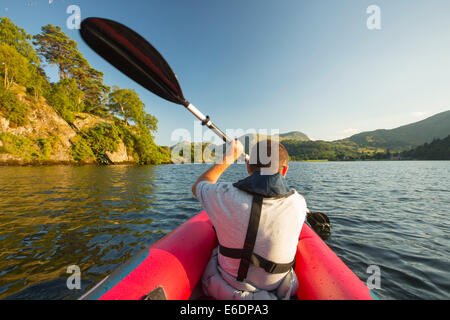 Un uomo di mezza età paddling in un kayak inflateable sull'Ullswater nel distretto del lago, UK. Foto Stock