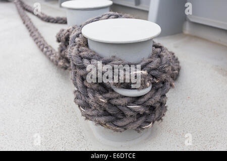 Close-up di una cima di ormeggio con una estremità annodata legato attorno un gancio su un molo in legno/ Nautico corda di ormeggio Foto Stock