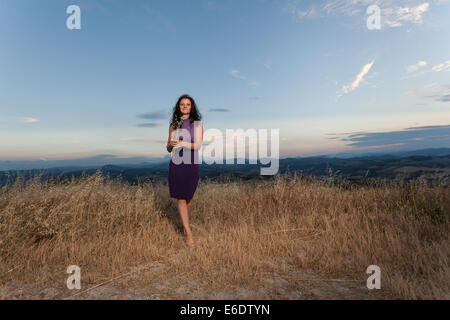 La donna caucasica in abito viola in campo Foto Stock