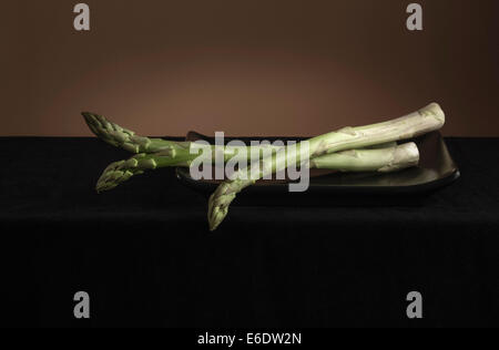 Asparagi in nero piatto sulla tovaglia scuro Foto Stock