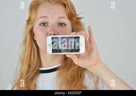 Ritratto di un auburn teen prendendo un autoritratto con un telefono. Foto Stock