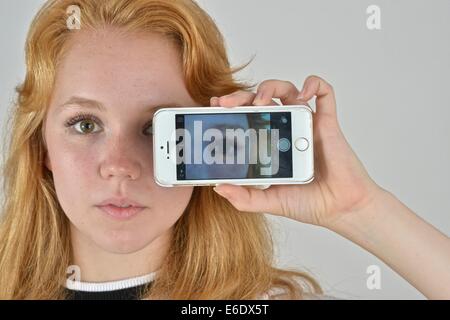 Ritratto di un auburn teen prendendo un autoritratto con un telefono. Foto Stock