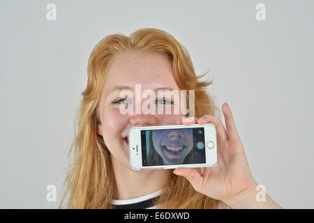 Ritratto di un auburn teen prendendo un autoritratto con un telefono. Foto Stock