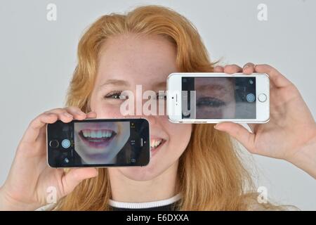 Ritratto di un auburn teen prendendo un autoritratto con un telefono. Foto Stock