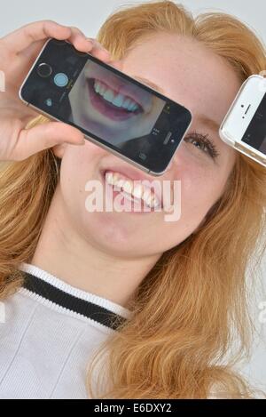 Ritratto di un auburn teen prendendo un autoritratto con un telefono. Foto Stock