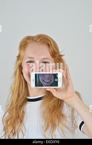 Ritratto di un auburn teen prendendo un autoritratto con un telefono. Foto Stock