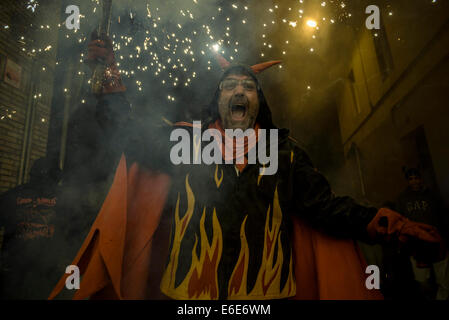 Barcellona, Spagna. 21 Ago, 2014. Un membro di 'la Vella de Gracia" rende i volti durante l'impostazione off il suo petardi durante il 'Correfocs' a 'Festa Major de Gracia'. - La Festa Major de Gracia, uno della Barcellona più vivaci festival, termina con correfocs (fire-corre), una delle caratteristiche più impressionanti in catalano festival. Tradizionalmente le strade sono prese in consegna dai bambini vestiti in costumi del diavolo. Credito: Matthias Oesterle/ZUMA filo/ZUMAPRESS.com/Alamy Live News Foto Stock