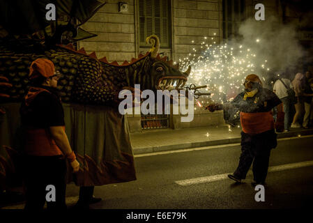 Barcellona, Spagna. 21 Ago, 2014. Un membro di 'la Vella de Gracia' lits draghi petardi durante il 'Correfocs' a 'Festa Major de Gracia'. - La Festa Major de Gracia, uno della Barcellona più vivaci festival, termina con correfocs (fire-corre), una delle caratteristiche più impressionanti in catalano festival. Tradizionalmente le strade sono prese in consegna dai bambini vestiti in costumi del diavolo. Credito: Matthias Oesterle/ZUMA filo/ZUMAPRESS.com/Alamy Live News Foto Stock